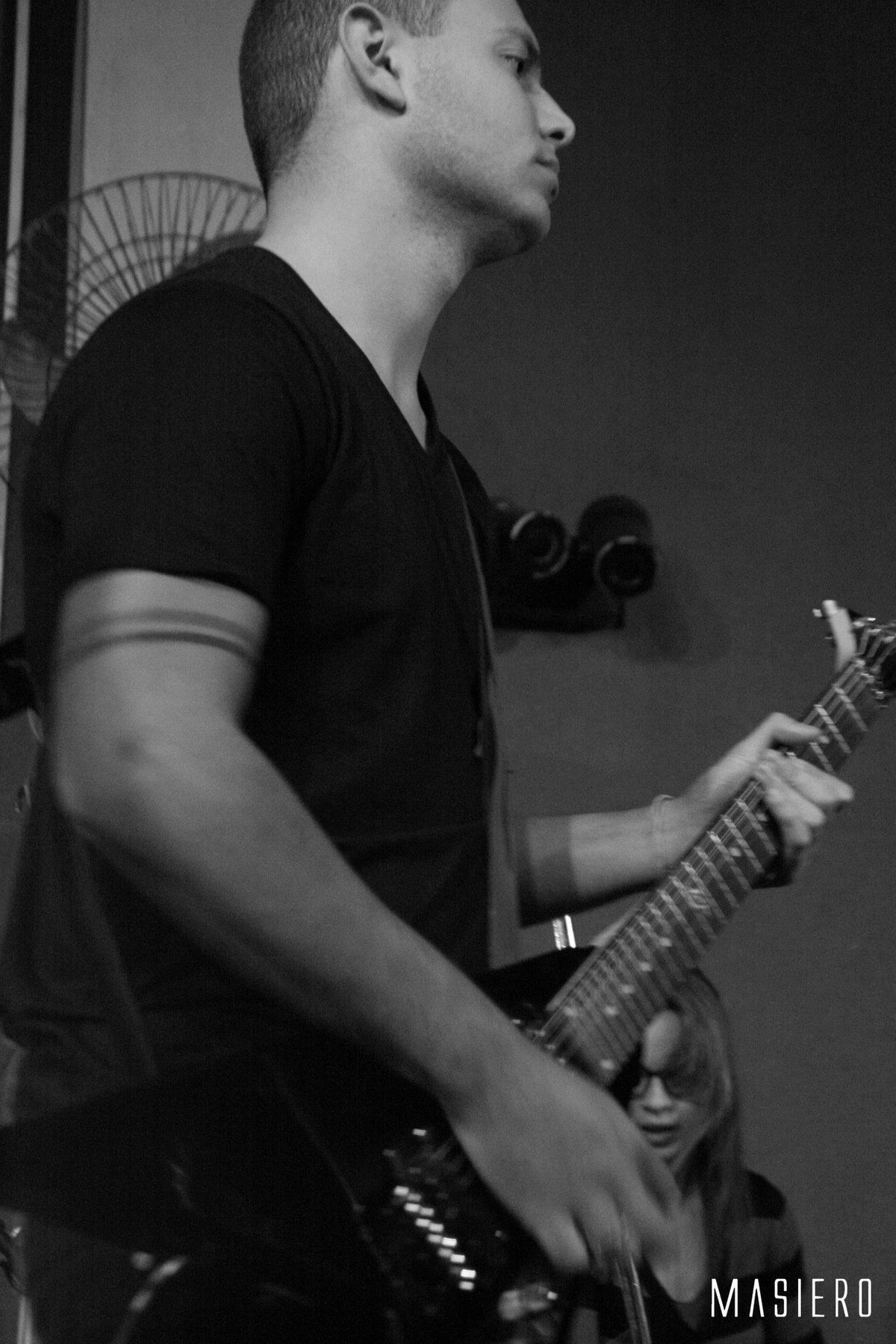 Guitarrista tocando no palco, em preto e branco.