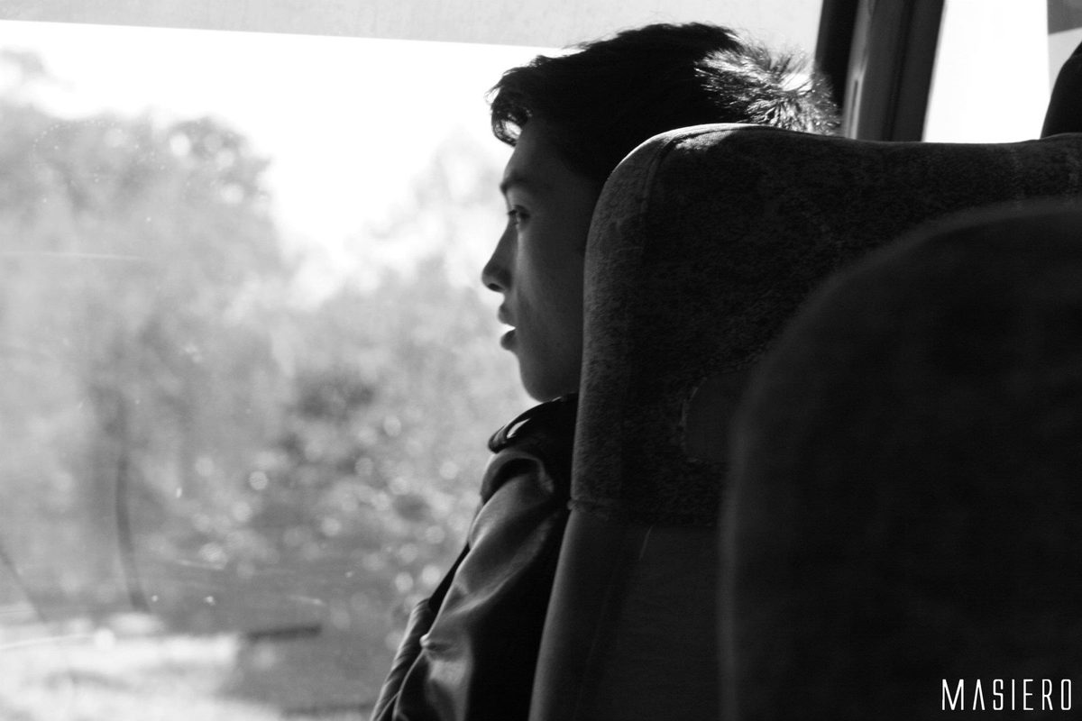 Integrante olhando pela janela do ônibus, em preto e branco.