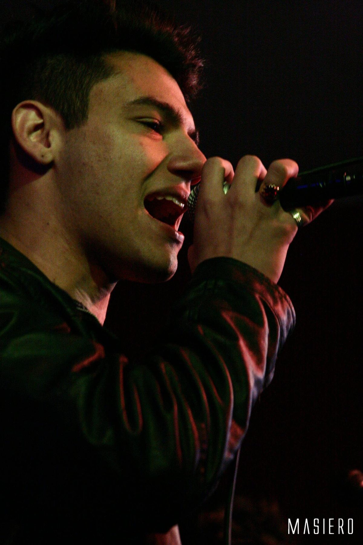 Vocalista cantando de olhos fechados, em close.