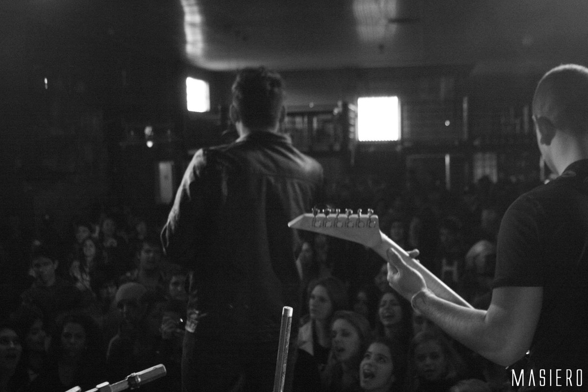 Show visto do fundo do palco, com o público à frente, em preto e branco.