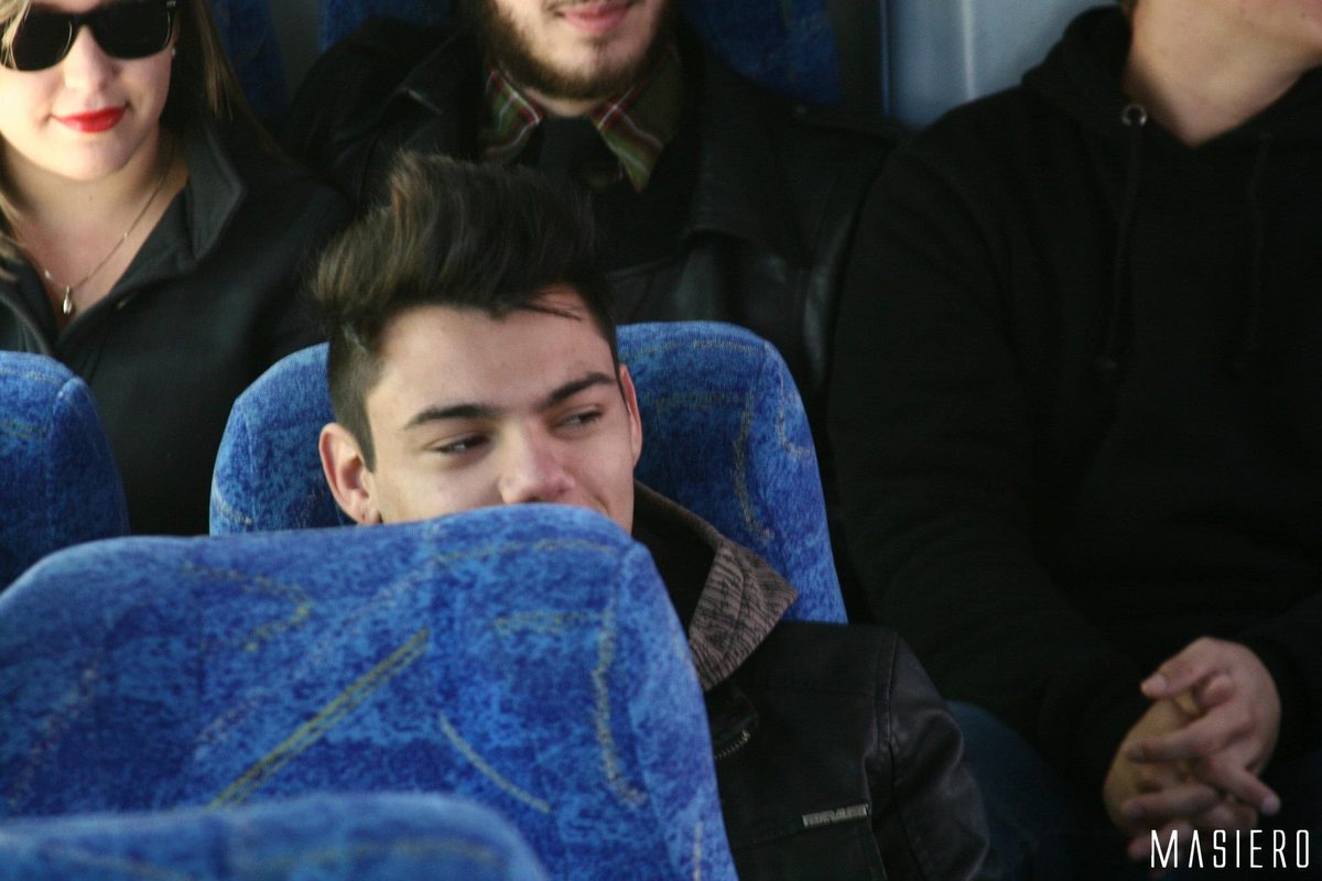 Integrante sorrindo entre as poltronas do ônibus.
