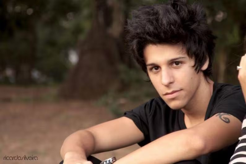 Retrato de Alex sentado, olhando para a câmera.