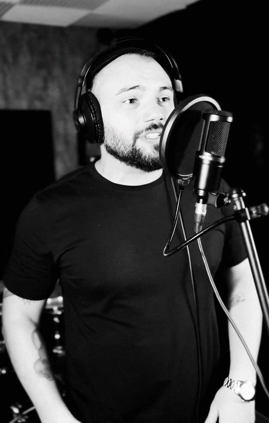 Matheus Orlando gravando voz para o EP Depois de Tudo, de fone de ouvido diante do microfone.